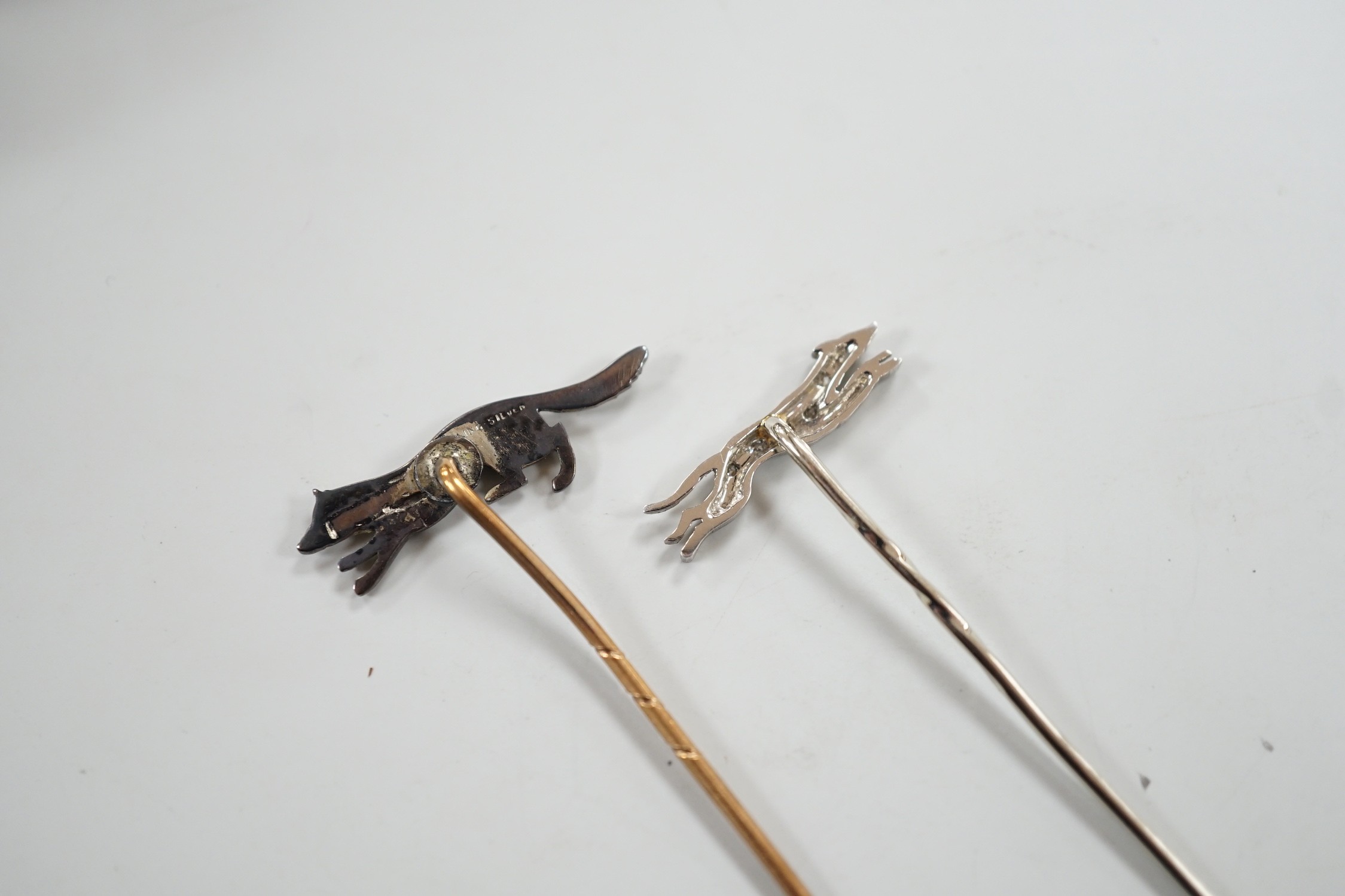 A mid 20th century white metal and diamond chip set hound stick pin, 57mm, in Asprey box and a similar paste set fox stick pin.